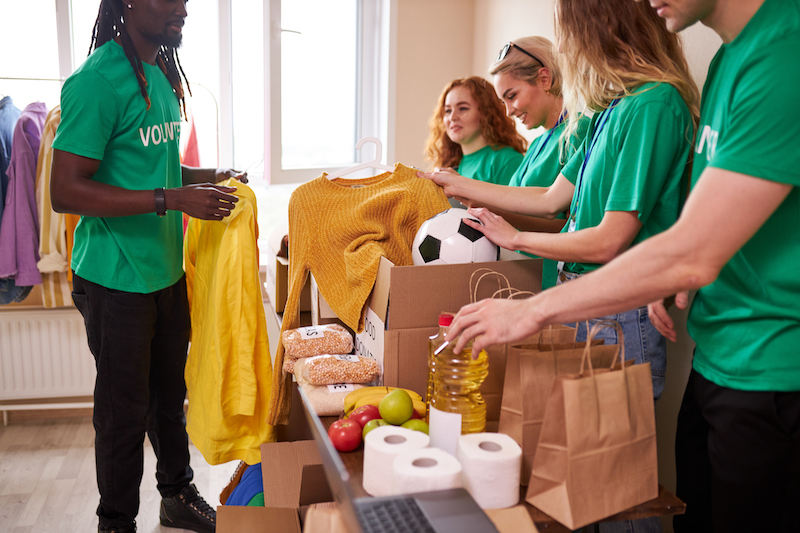 group of young people volunteering by folding clothes, filling bags